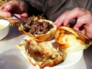 Spooning meat and onions and broth from samsa
